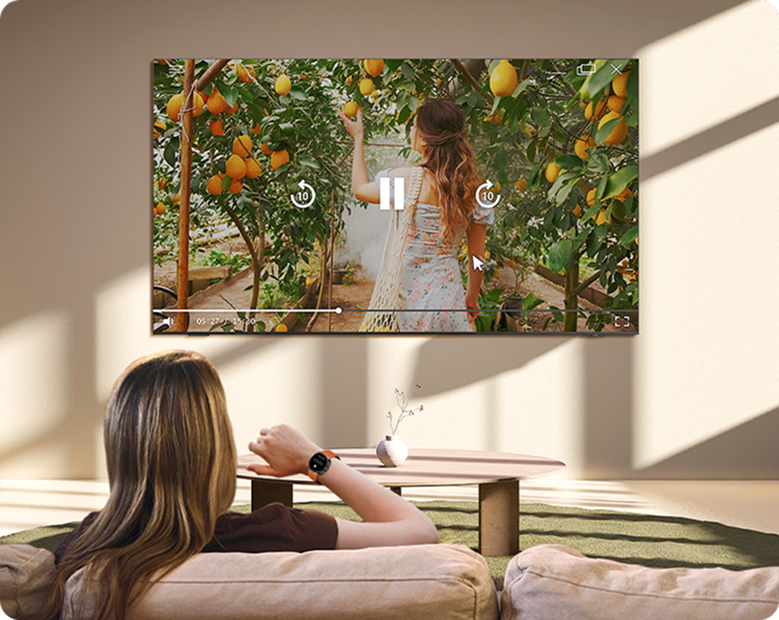 Kobieta sterująca telewizorem Samsung ruchem ręką z Galaxy Watch